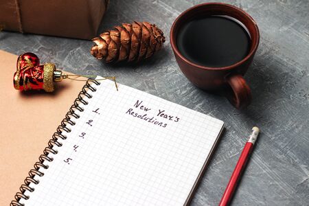 New Year's resolution, text on the paper in notepad, promises concept, pencil, coffee cup, decorations.の写真素材