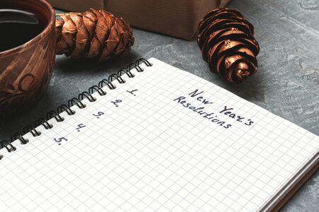 New Year's resolution, text on the paper in notepad, promises concept, pencil, coffee cup, decorations.の写真素材