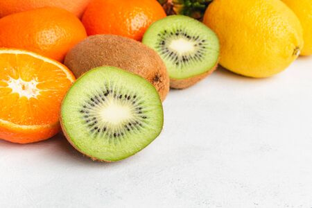 Kiwi and orange sliced halves, tropical fruits on textured white background.の写真素材