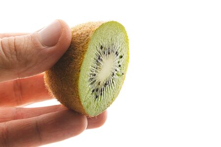 Hand holds sliced half of kiwi fruit isolated on white background.の写真素材