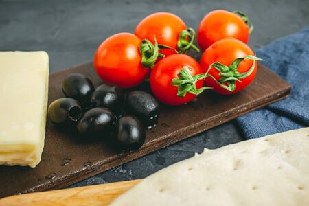 Black olives, cherry tomatoes, mozzarella cheese, dough, ingredients to pizza cooking.