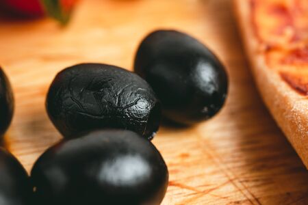 Black olives on wooden board, close-up view.の写真素材