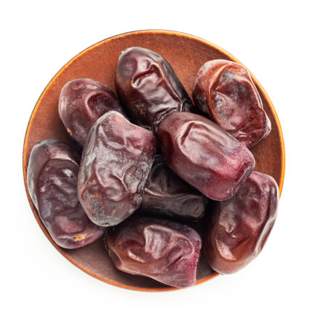 Dried organic date fruits in a plate, top view, isolated on white background.