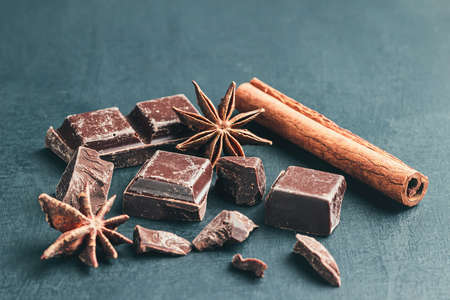 Chopped chocolate cubes, cinnamon stick and star anise on dark background with copy space, close-up view.の写真素材