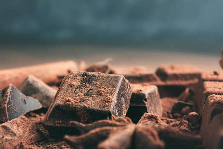 Chopped chocolate cubes with cocoa powder and star anise on dark background with copy space, close-up view.の写真素材