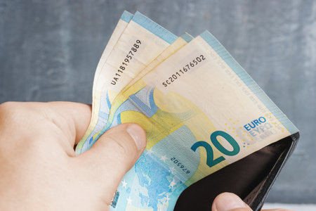 Male hands taking out money of his wallet, notes of twenty euros.