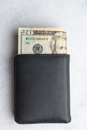 Wallet with twenty dollar bill money on a white table.