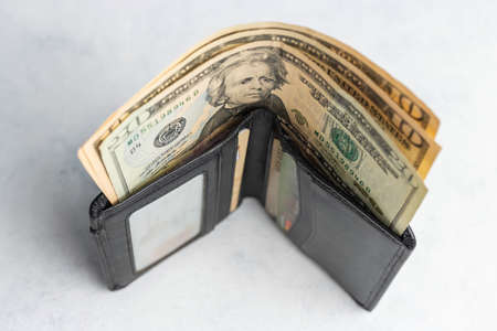 Wallet with cash, twenty dollar bills money on a white table.