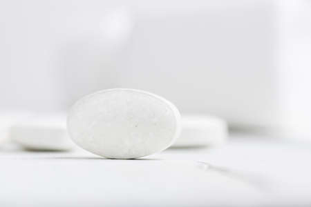White pills at white wooden planks, medication treatment, close-up view.