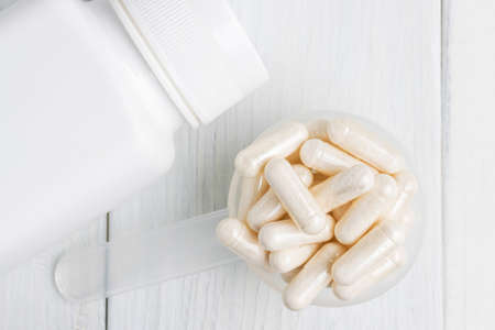 White pills or capsules in a plastic spoon, medication treatment, alternative medicine, close-up,...