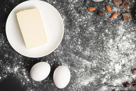 Raw food ingredients, butter, eggs, nuts for baking on a dark background, prepare for cooking, top view.の写真素材