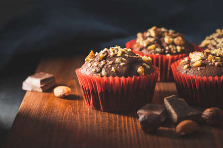 Homemade chocolate muffins or cupcakes sprinkled of nuts on a wooden board.