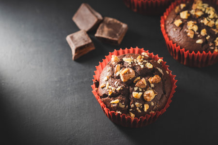 Homemade chocolate muffins or cupcakes sprinkled of nuts on dark background.の写真素材
