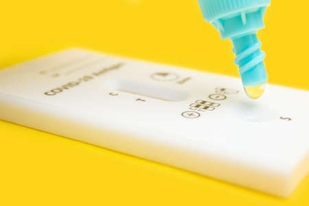 Process of testing with rapid antigen test kit for viral disease COVID-19 on yellow background.