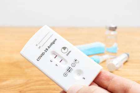 Hand holds rapid antigen test kit for viral disease COVID-19 with positive result, copy space.