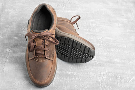 Mens brown leather walking shoes on textured background.