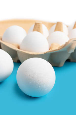 White chicken eggs in carton box on blue background.の写真素材
