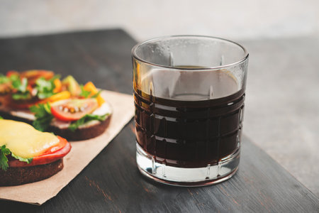Breakfast with glass of americano coffee and sandwiches on a dark wooden board.の写真素材