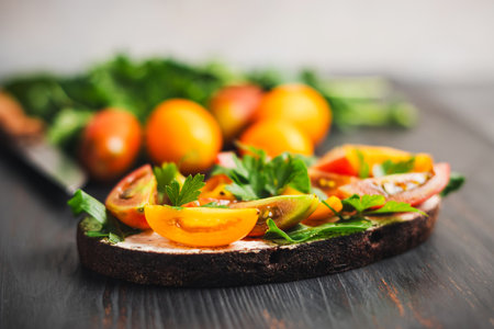 Healthy vegetarian sandwich with toasted bread, cheese, arugula, parsley and tomatoes on a dark wooden board.の写真素材