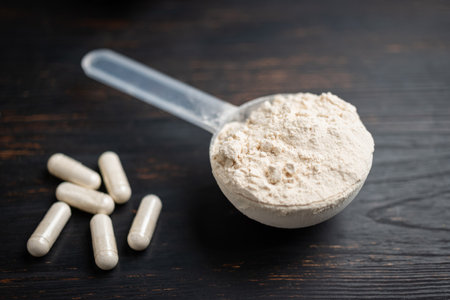 Scoop of whey or soy protein powder, white capsules of amino acids, vitamins and creatine,...