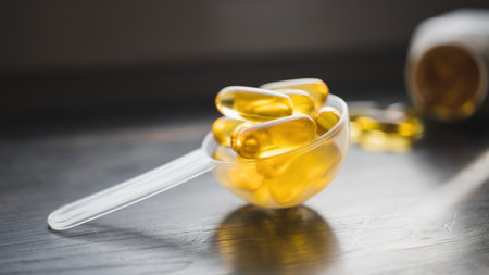Omega 3 fish oil yellow capsules in a plastic measuring spoon, dietary supplement on dark wooden board, healthy eating concept, close up view.の写真素材