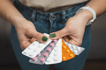 Young woman holds a medicine, various blister packs with pills for treatment, close-up view.の写真素材