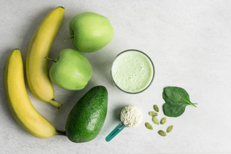 Green detox smoothie, blended vegetarian drink, protein milkshake in a glass from spinach, banana, apple, avocado and seeds on a table, healthy eating concept, top view.の写真素材
