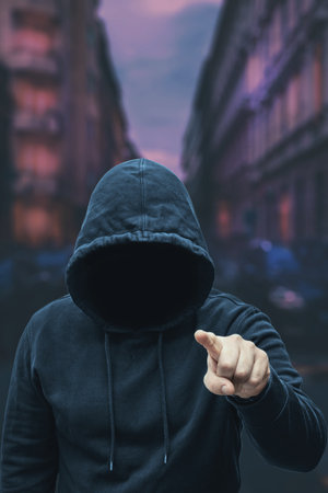 Mysterious faceless hooded anonymous criminal, silhouette of bandit, terrorist or gangster on night...