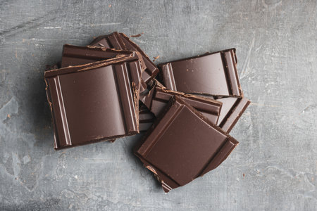 Heap of delicious dark chocolate pieces or cubes, chopped, broken chocolate bar on a dark background, top viewの写真素材