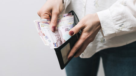 Woman's hands taking out money from wallet, Ukrainian Hryvnia banknote cash.の写真素材