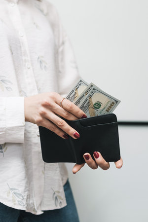 Woman's hands taking out money from wallet, dollar banknote cash.の写真素材