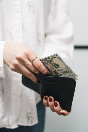 Woman's hands taking out money from wallet, dollar banknote cash.の写真素材