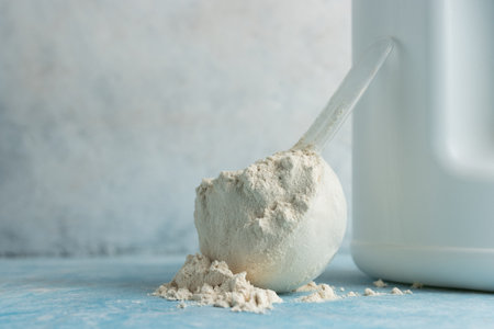 Whey protein powder in measuring spoon on a blue background.の写真素材