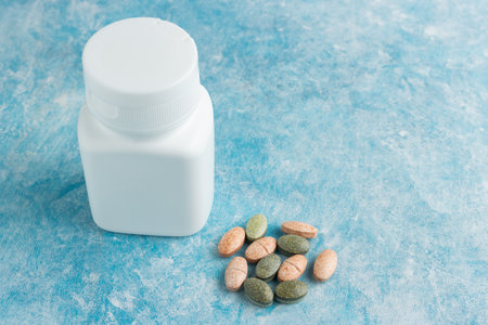 Multicolored medical pills, drugs or tablets for treatment on blue background, vitamins and minerals, nutritional or dietary supplement.の写真素材
