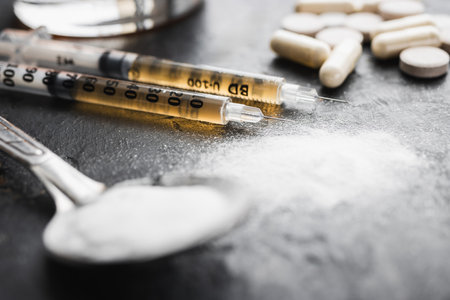 Narcotic substances in spoon, dope powder in transparent plastic bag, syringes with drugs dose, white pills on dark textured background. Concept of addiction and bad habits.の写真素材