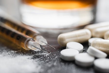 Narcotic substances, dope powder, syringes with drugs dose, white pills and glass of alcohol drink on dark textured background. Concept of addiction and bad habits.の写真素材