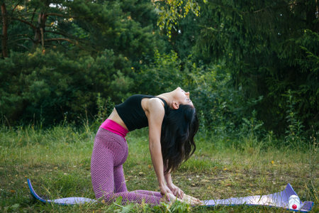 A young sporty woman doing yoga exercises, morning workout in the park, outdoors.