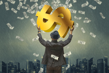 Back view of business man hug money & money symbol with green tones dramatic rain & city background. Concept for success business. Motion blur money.の写真素材