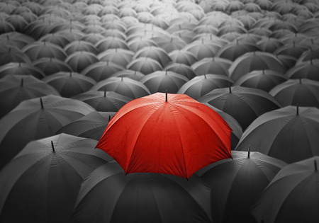 Outstanding Red umbrella among many dark crowd. Selective focus, shallow depth of field.の写真素材