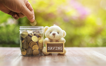 Hand putting money (coins) in the glass with FUEL notes Investment and Interest Concept. Filter soft effect and warm sunset selective focus.の写真素材
