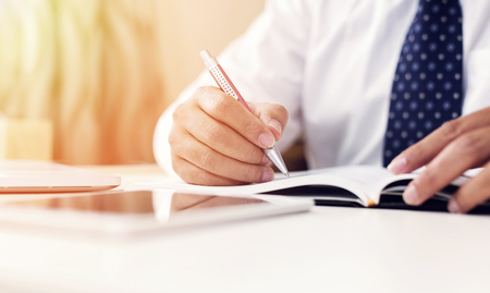 Businessman hands with pen writing on notebook. Selective focus, shallow depth of field.の写真素材