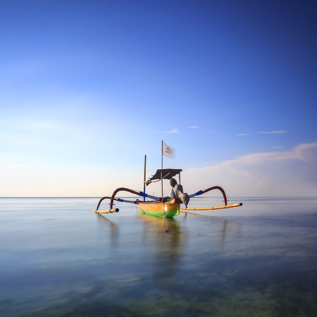 Bali, Indonesia. Fishing boats populate the shoreline at the Sanur Beach with long exposure settingの写真素材