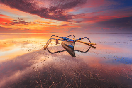 Balinese jukung fishermen with beautiful sunrise in Bali, Indonesiaの写真素材
