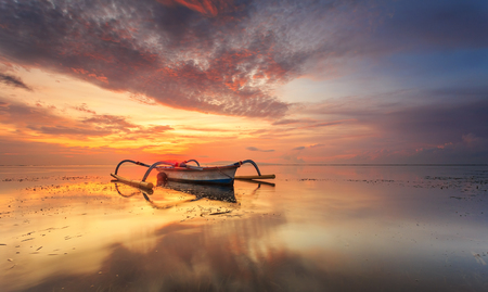Balinese jukung fishermen with beautiful sunrise in Bali, Indonesiaの写真素材