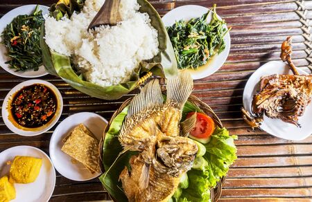Traditional Sundanese meal of rice. Accompanied with salted fish, fried chicken, tempeh, tofu, vegetables dishes and chiliの写真素材