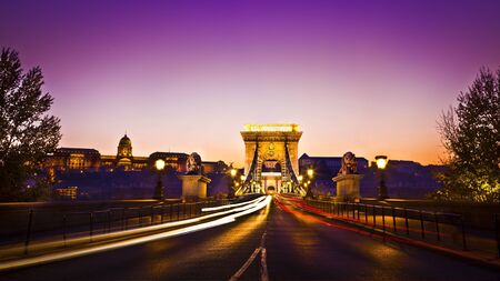 The lit  of the Szechenyi Chain Bridge is a suspension bridge that spans the River Danube of the beautiful, decorative Budapest, the capital city of Hungary at nightの写真素材