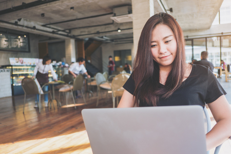 A woman sitting and using laptop in modern loft cafeの写真素材