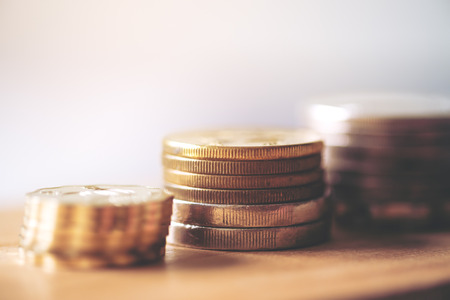 Coins stack on wooden table with blur background
