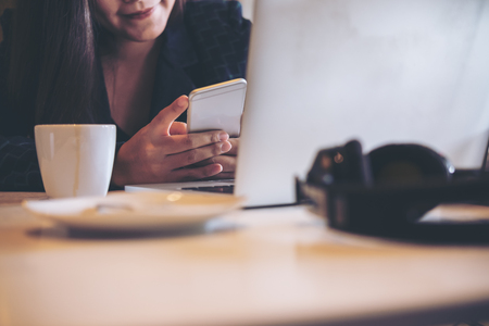 A business woman holding and using smart phone and laptop in officeの写真素材