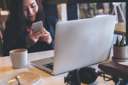 A business woman holding and using smart phone and laptop in officeの写真素材